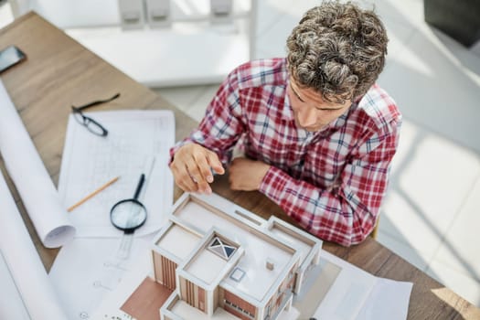 Male architect holding and working on model of architectural house top view
