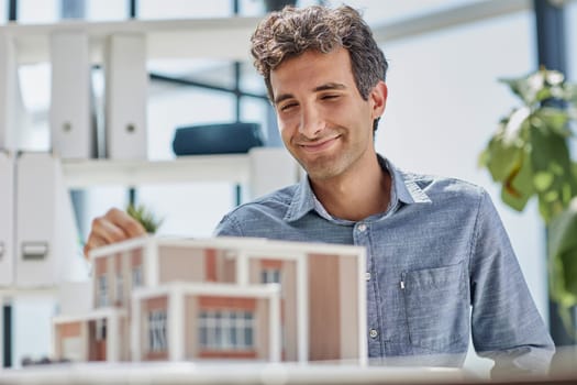 young caucasian engineer man making building model with the use of drawings and notes in office.