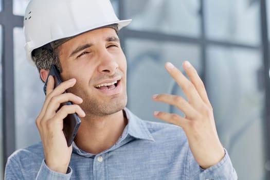 smiling architect in a hard hat speaks on a smartphone.
