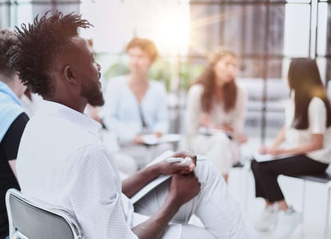 portrait of an African American in a white shirt against the background of his colleagues. looking at the camera