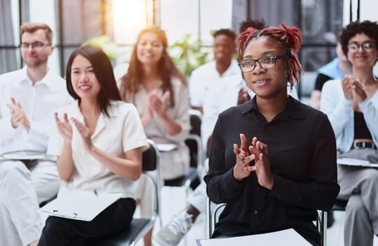 Selective focus of young businesswoman applauding together with interracial colleagues during seminar, banner
