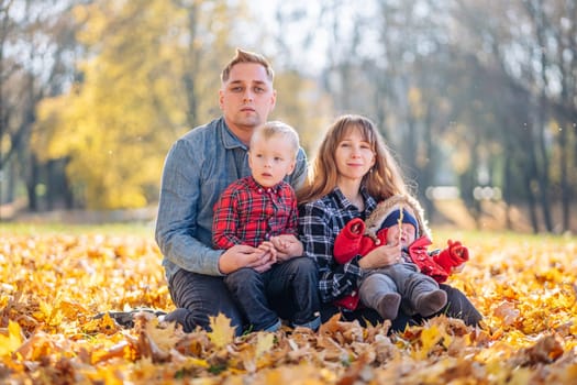 A young family sits in the park on a leafy, sunny autumn day