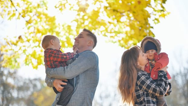 A young, funny family with kids in the park in the fall