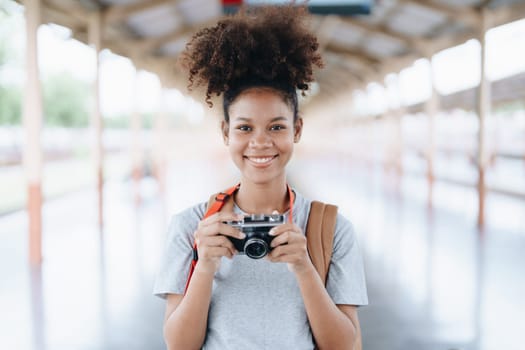 Asian teenage girl african american traveling using a camera take a photo to capture memories while waiting for a train at the station