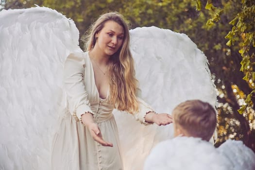Olstrup, Denmark, June 6, 2023: Girl angel with her son in the evening garden