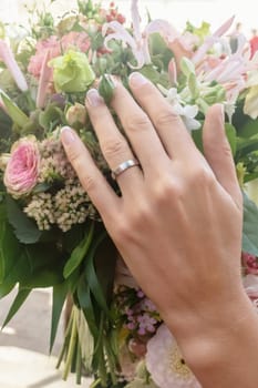 Hands and rings on wedding bouquet