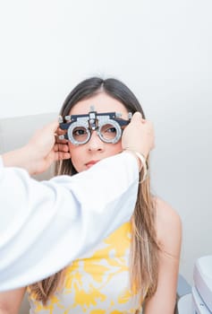 Doctor adjusting vision of patient with optometrist trial frame. ophthalmologist examining girl with optometrist trial frame