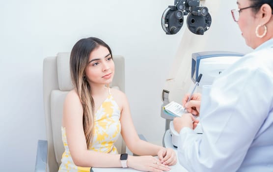 Female patient having consultation with optometrist in office. Optometrist with female patient taking notes in office.