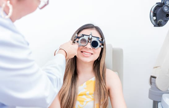 Smiling patient with optometrist trial frame. Closeup of optometrist examining patient with optometrist trial frame