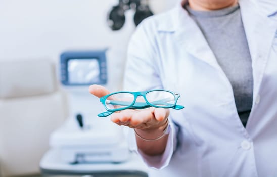 Optometrist hands showing a glasses. Oculist giving glasses in palm hand. Eyeglasses and visual health concept