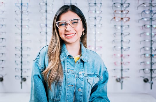 Smiling happy girl in eyeglasses with store eyeglasses background, Portrait of happy girl in glasses in an eyeglasses store