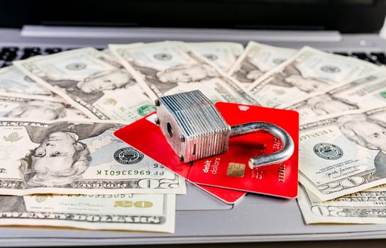 Close up of Padlock on top of credit card on dollar bills, Concept of credit card information theft. Padlock with credit card on top of dollars