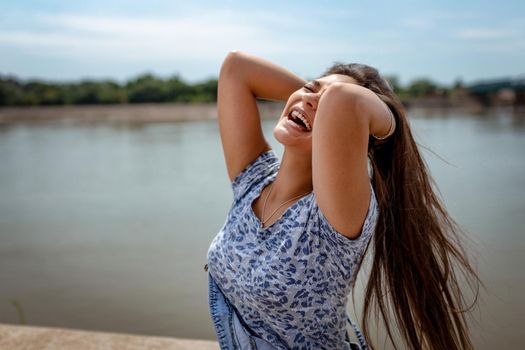 A beautiful cheerful gir having fun with your hair in the open and enjoying on the city rivershore on a beautiful summer day.