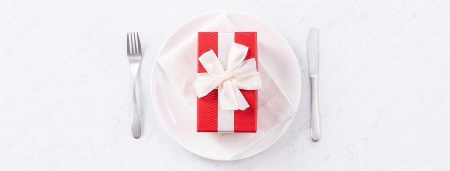 Valentine's Day, Mother's Day, holiday dating meal, banquet design concept - White plate and red ribbon on marble background, top view, flat lay.