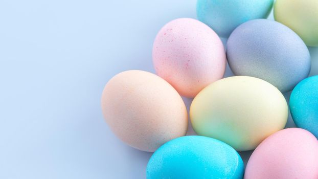 Colorful Easter eggs dyed by colored water isolated on a pale blue background, design concept of Easter holiday activity, close up, copy space.