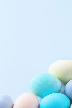 Colorful Easter eggs dyed by colored water isolated on a pale blue background, design concept of Easter holiday activity, close up, copy space.