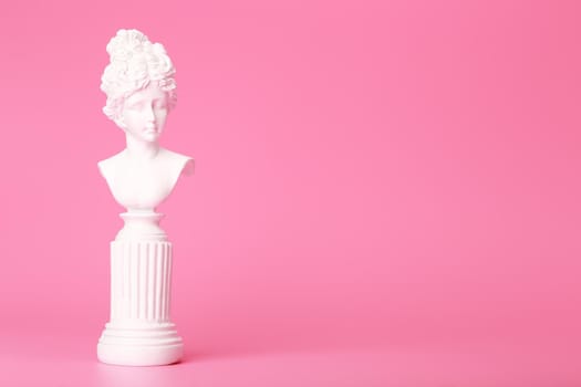 White gypsum woman statue against pink background with copy space. Concept of template for website or commercial banner