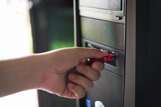 Close up of a woman hand plugging a pendrive on computer