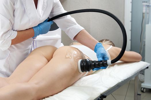 Woman getting anti-cellulite and anti-fat therapy in beauty salon. Hardware cosmetology. Body care. Spa treatment. Ultrasound cavitation body contouring treatment.