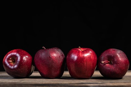 Red apple on wood table, black background