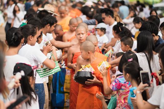 LAMPANG, THAILAND - JULY 9, 2017: Unidentified people offer food to monks in Devo tradition on JULY 9, 2017 in Lampang, Thailand. Tak Bat Devo is the tradition in end of Buddhist Lent.