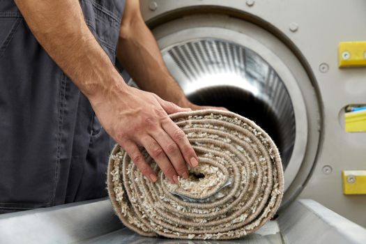 Laundry worker in the process of working on the automatic machine for drying carpets