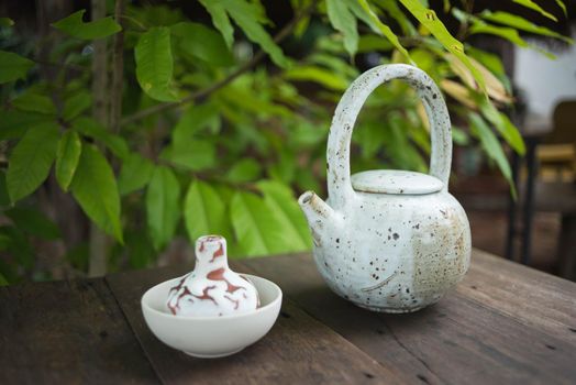 Clay pot of  iced butterfly pea tea on wooden table