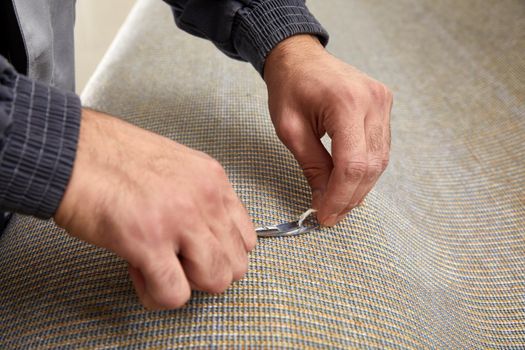 Closeup of hand cutting off string on a carpet with scissors