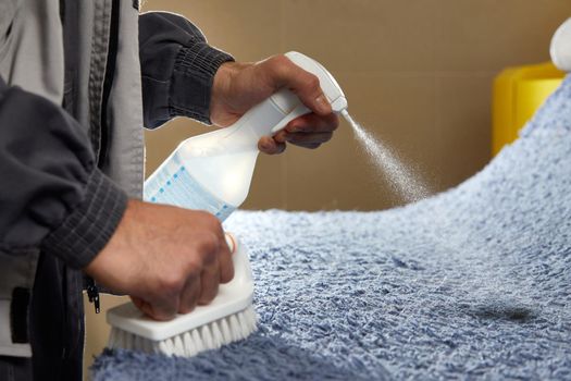 Man Spraying Detergent On Grey Carpet To Remove Stain in professional cleaning service High quality photo