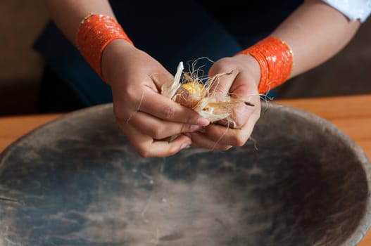 closeup of indigenous woman's hands manipulating the dried leaves of an ear of corn over a wooden bowl. High quality photo