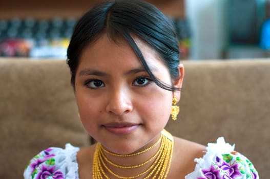 closeup of beautiful indigenous colombian teenager with gold jewelry looking at camera. High quality photo