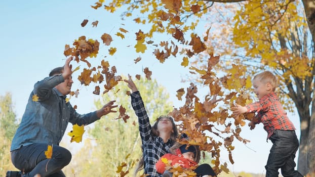 A happy family in an autumn park having fun and crumbling leaves