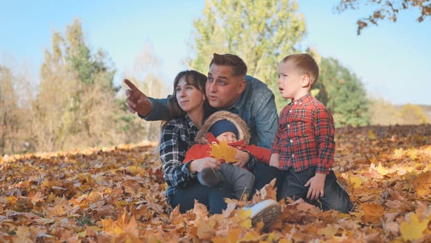 A happy family in an autumn park having fun and crumbling leaves
