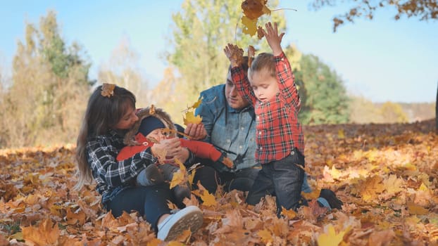 A happy family in an autumn park having fun and crumbling leaves