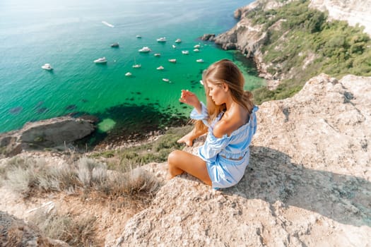 Woman travel sea. Happy woman in a beautiful location poses on a cliff high above the sea, with emerald waters and yachts in the background, while sharing her travel experiences.