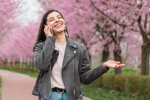 Cheerful beautiful woman with wide and beautiful smile on the phone with a beloved walking in the park.