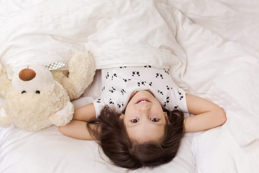 cute little child girl wakes up from sleep in bed in the morning. top view