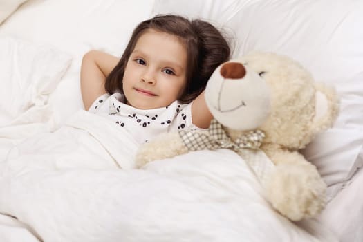 cute little child girl wakes up from sleep in bed in the morning