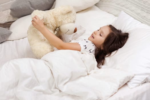cute little child girl wakes up from sleep in bed in the morning