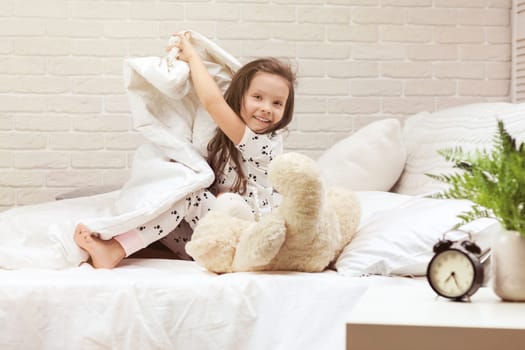 cute little child girl wakes up from sleep in bed in the morning