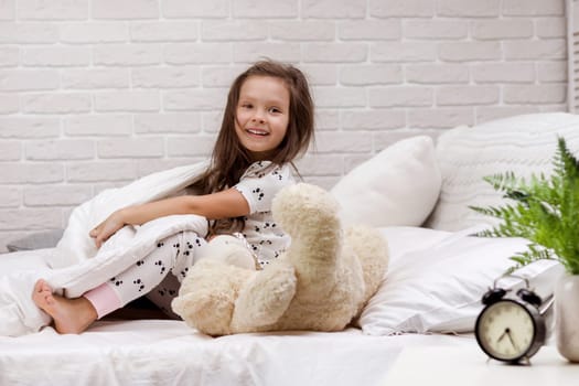 cute little child girl wakes up from sleep in bed in the morning