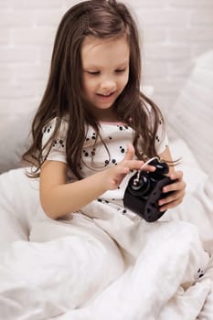 cute happy little child girl in pyjamas with clock in bed. good morning