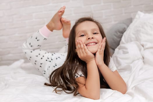 cute happy little child girl in pyjamas in bed. good morning