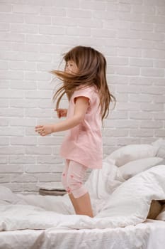 cute little child girl fooling around in bed. child jumping on bed