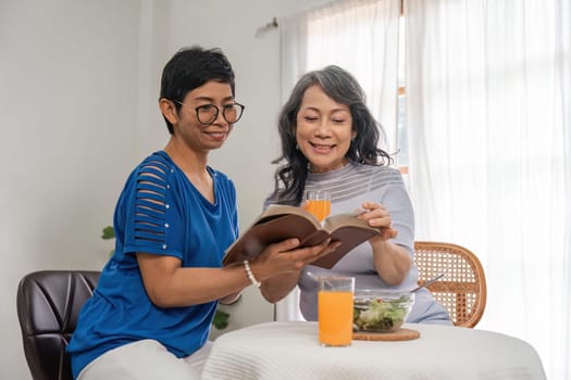 Two retired sisters their while enjoy eating healthy food together in living room.