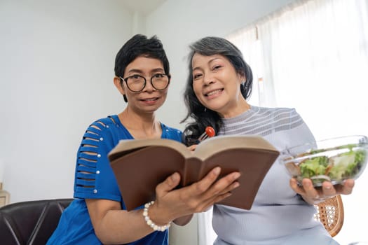 Two retired sisters their while enjoy eating healthy food together in living room.