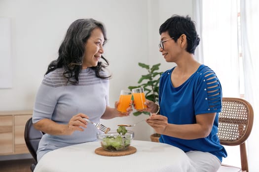 Two elderly girl friend enjoy eating healthy food at house.