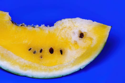 A slice of sweet fresh yellow watermelon served on a blue dish, against colorful background.