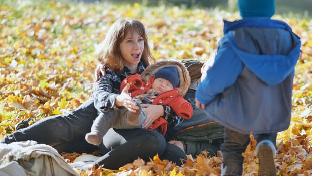 A family and their children enjoy the golden fall in the park sitting on the leaves