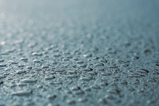 Raindrops on fresh asphalt. water drops on black. Abstract black background with drops. Highway covered with water drops, copy space. Water on the sidewalk